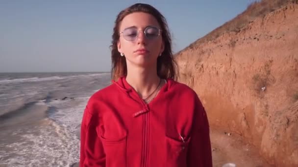 Een meisje met gesloten ogen in het midden van het frame, wind ontwikkelt haar op zee — Stockvideo