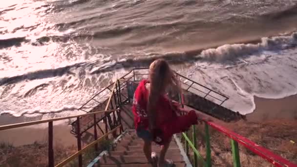 Meisje gaat van de oude trappen op het strand naar de zee — Stockvideo