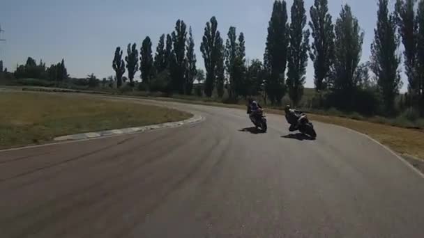 Bicicleta preta ultrapassa rapidamente o motociclista azul na virada da pista — Vídeo de Stock