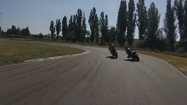 Svart cykel snabbt passerar den blå motorcyklisten vid svängen av racetrack — Stockvideo