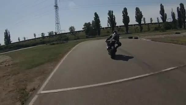 ZAPORIZHIA, UCRÂNIA - JUNHO 17, 2019: piloto preto em couro passeios de motocicleta ao longo de uma pista de corrida virando à esquerda e à direita . — Vídeo de Stock