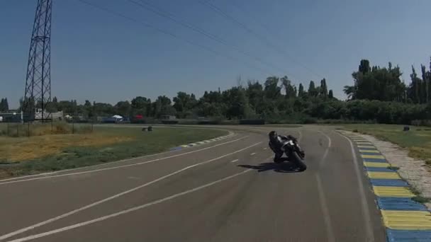 Een motorrijder op een fiets trekt van een circuit, ronde, voor een pauze — Stockvideo