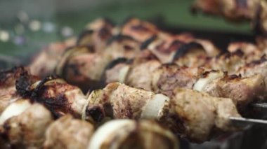 Yakın plan. El, şişleri kızartılması için kızarmış etle çevirir..