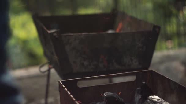 Detailní záběr. Ruka rozdmýchává oheň lopatou v grilu — Stock video