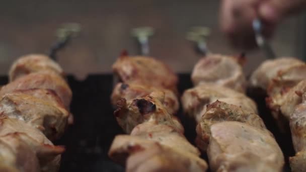 Zbliżenie. Ręka przekręca szaszłyki smażonym mięsem dla jednolitego smażenia. — Wideo stockowe