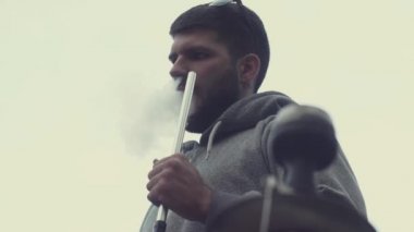 Beyaz arka planda nargile tüttüren sakallı şık bir adam. Yukarıdan görüntüle