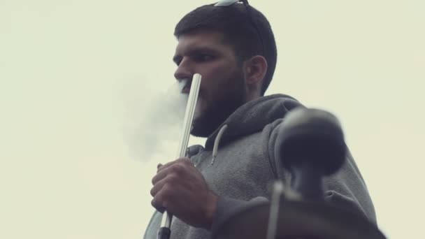 Stylish guy with beard smoking hookah on white plain background. View from above — Stock Video