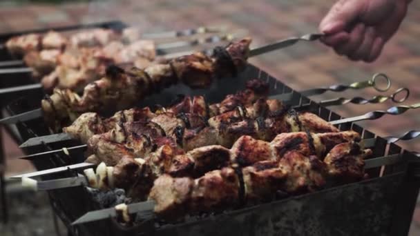 Close-up. Mão torce espetos com carne de porco marinada para fritar uniforme na grelha — Vídeo de Stock