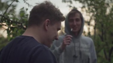 Adam bir arkadaşının taşrada, akşamleyin, bahçede yaptığı komik şakaya gülüyor.