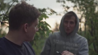 Genç, şık, modaya uygun erkekler, şaka yapıyor, elektronik sigara içiyor, gülüyor.