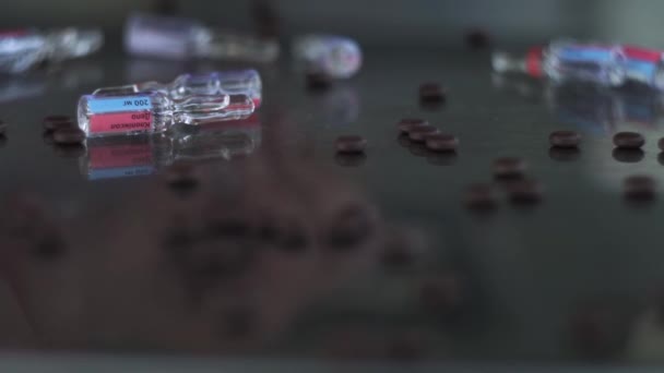 Vingers met een ring, verzamelen verspreide ampullen op een medische, metalen, spiegeltafel, tussen bruine tabletten. Statische camera — Stockvideo
