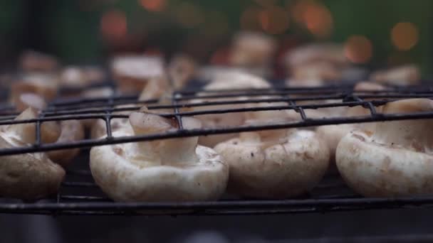 Närbild. Svampar kokas på grillen på en grill, på en grön bakgrund av eld, gnistor — Stockvideo