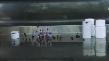 Birçok kahverengi hapın yakın plan düşüşü gri, metalik, aynalı masa, yavaş çekim.