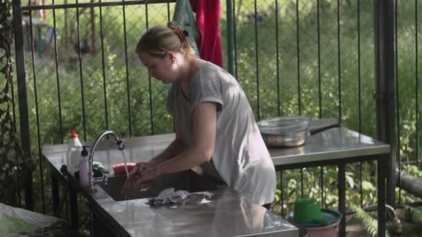 Mulher lavando com uma esponja ensaboada um frasco de vidro na cozinha, na casa de campo de verão — Vídeo de Stock