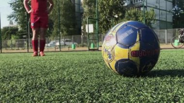 ZAPOROZHYE, UKRAINE - 8 HAZİRAN 2020: kırmızı ayakkabılı genç adam futbol sahasında ağır topa vuruyor. Yeşil çimenler, beyaz çoraplar, güçlü bir tekme, futbol oynamak.