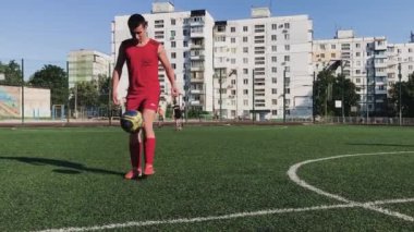 ZapOROZHYE, UKRAINE - 8 Temmuz 2020: kırmızı üniformalı adam topa vuruyor. Bahçedeki mini futbol sahasında.