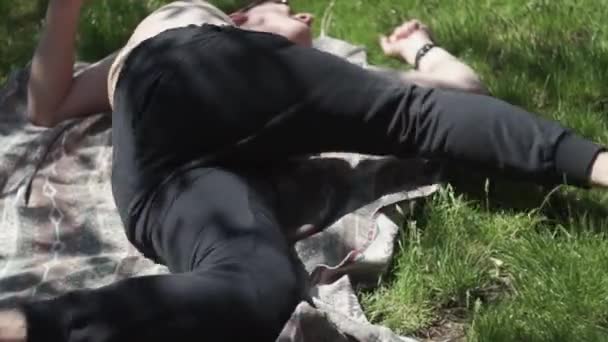 Funny man on the lawn, runs lying on the lawn, without a T-shirt in black pants — Stock Video