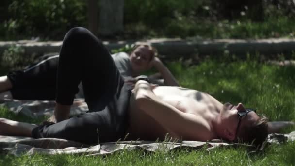Młoda dziewczyna i chłopak odpoczywają, relaksują się na trawie, trawniku, w domku letniskowym — Wideo stockowe