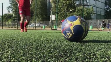 ZAPOROZHYE, UKRAINE - 8 HAZİRAN 2020: kırmızı ayakkabılı genç adam futbol sahasında ağır topa vuruyor. Yeşil çimenler, beyaz çoraplar, güçlü bir tekme, futbol oynamak.