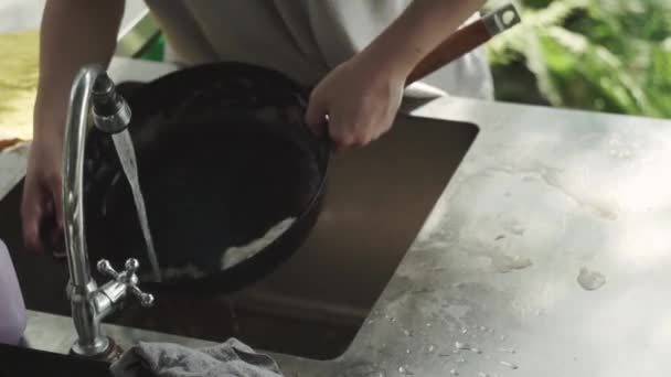 Las manos de la mujer lava espuma de la sartén, bajo el agua corriente, lavabo de metal, cocina, casa de campo de verano — Vídeo de stock