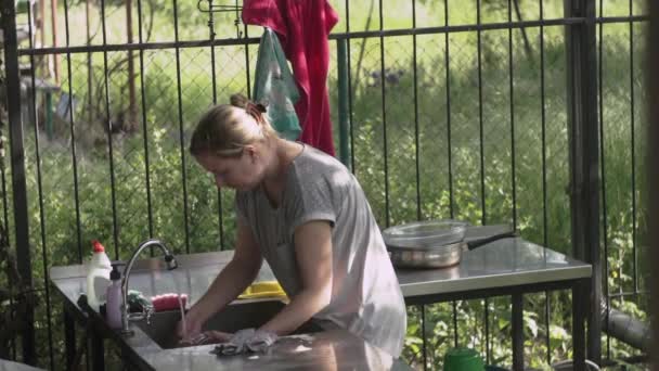 Mujer lavando con una esponja jabonosa un frasco de vidrio en la cocina, en casa de campo de verano — Vídeo de stock