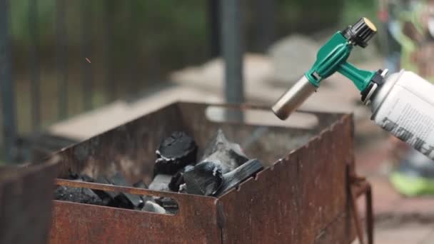 Man steekt barbecue aan met een gasbrander — Stockvideo