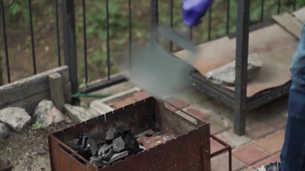 Kille i handskar, huk, gör eld, rätar ut kol med händerna, tändning — Stockvideo