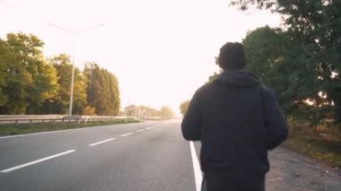 Sporcu şafak vakti asfaltta pistte koşar. Arabalar geçiyor.