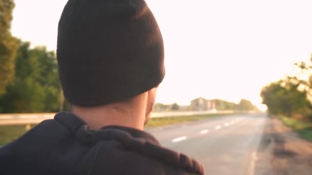 Close-up, atleta corre ao longo da pista, ao amanhecer, no asfalto. Os carros estão a passar — Vídeo de Stock