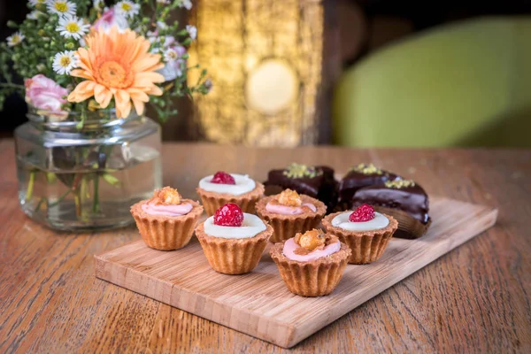 Different types of homemade mini cupcakes, served on a wooden board.