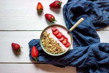 Beyaz ahşap zemin üzerinde çilek ile Granola.