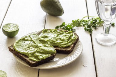 Beyaz ahşap arka plan üzerinde avokado ile Sandviçler.