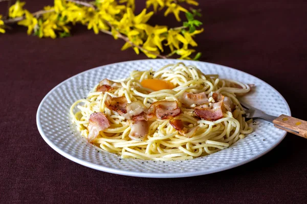 Pasta Carbonara. Flores en el fondo. Comida italiana . — Foto de Stock