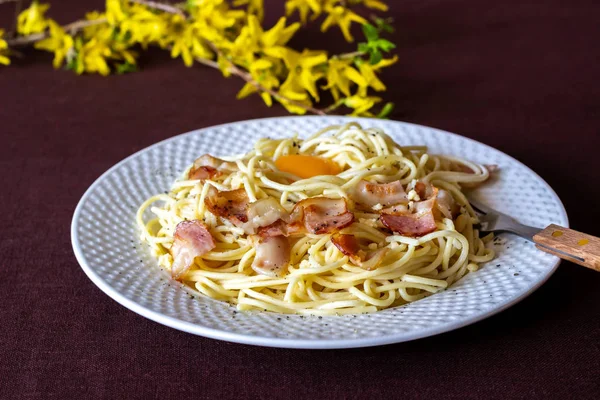 Makarna Carbonara. Arka planda çiçekler var. İtalyan yemekleri. — Stok fotoğraf