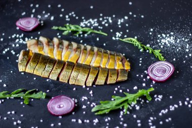 Soğan ve arugula ile koyu bir arka plan üzerinde ringa balığı ve uskumru