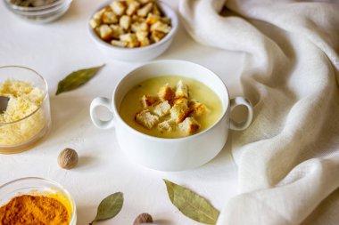 Beyaz arka planda peynirli krema çorbası. Beyaz ekmek kruton. Malzemeler.