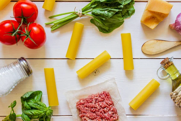 Cannelloni, tomates, carne picada e outros ingredientes. Fundo de madeira branco. Cozinha italiana . — Fotografia de Stock