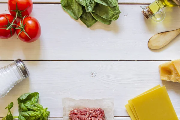 Lasanha, tomates, carne picada e outros ingredientes. Fundo de madeira branco. Cozinha italiana . — Fotografia de Stock