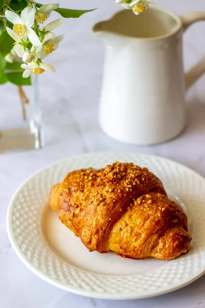 Um croissant e café em um fundo de mármore. As flores. Café da manhã . — Fotografia de Stock