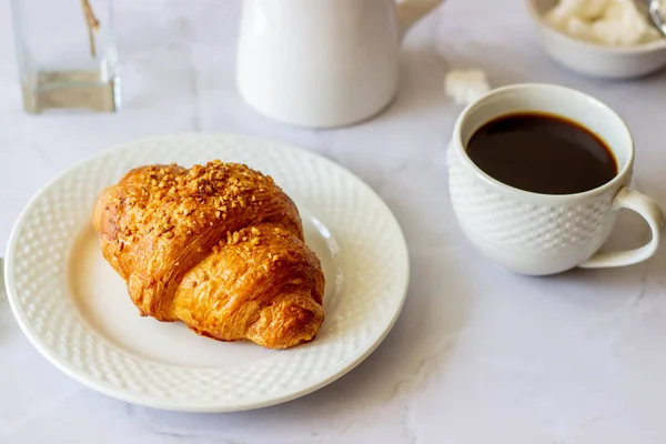 Ein Croissant und Kaffee auf Marmorgrund. die Blumen. Frühstück. — Stockfoto