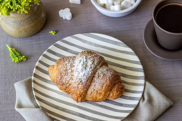 Croissant a káva na šedém pozadí. Květiny. Snídaně. — Stock fotografie