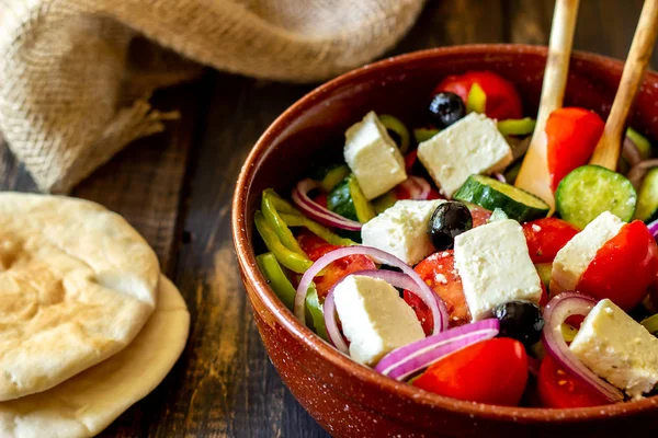 Griechischer Salat auf einem hölzernen Hintergrund. Tomaten, Paprika, Oliven, Käse, Zwiebeln. Gesunde Ernährung. Ernährung. Vegetarisches Essen. — Stockfoto