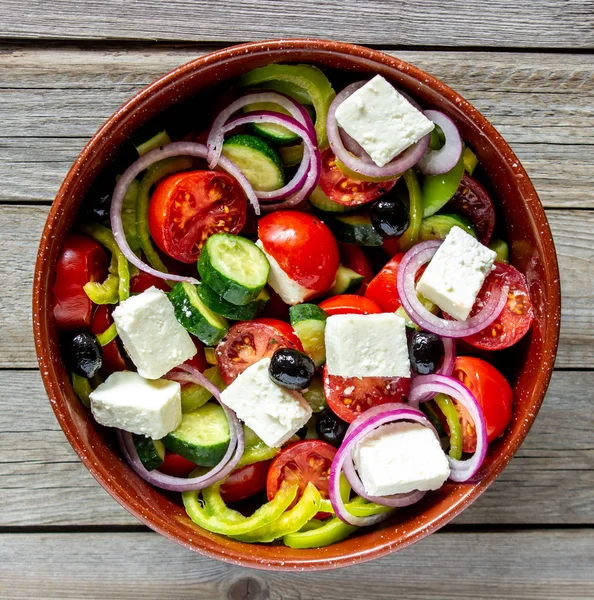 Greek salad on a wooden background. Tomatoes, peppers, olives, cheese, onions. Healthy eating. Diet. Vegetarian food.