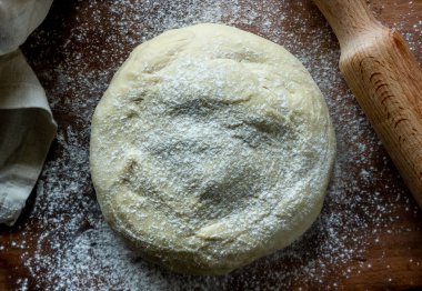Hamur ahşap bir arka plan üzerine un serpilir.