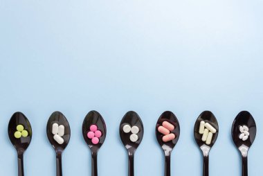 Mavi arka planda haplı kaşıklar. İlaçlar. İlaç tedavisi. Sağlık