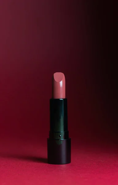 Lipstick on a dark red background. Cosmetics. Mock-up