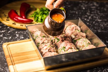 Çiğ domuz eti köfte, domates soslu metalik pişirme çanağı içinde