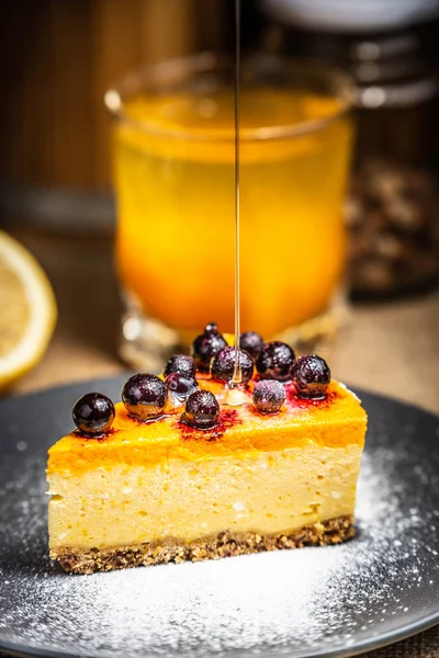 Slice of cheesecake with berries on a blue plate. Thick dripping