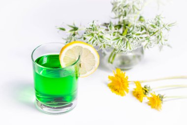 Limon bir dilim ile bir bardak şeffaf yeşil içecek.