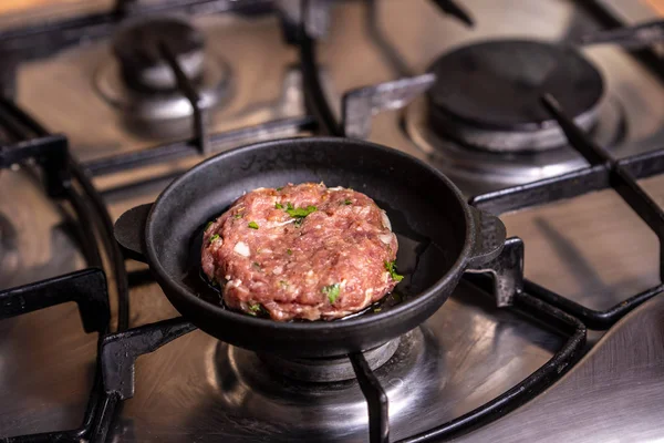 Iron pan with raw cutlet on a gas stove. — Stock Photo, Image